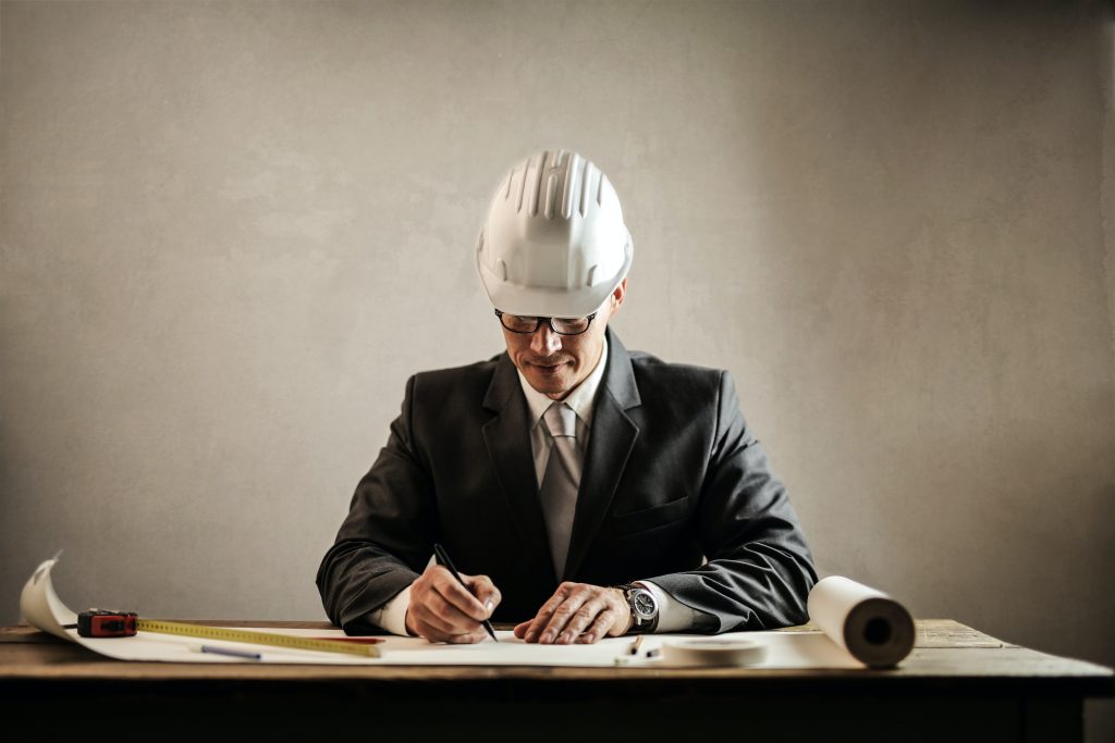 project manager in a suit with a hard hat on writing down plans
